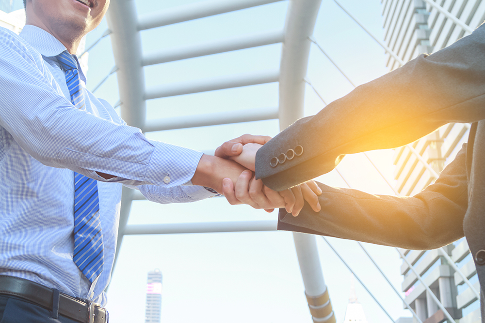 Two professionals shaking hands symbolizing collaboration and partnership in the EU BIO4COAT project on sustainable biobased coatings.